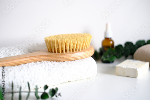 Massage wooden body brush on the background of spa items. Homemade body care. Dry lymphatic drainage massage and spa treatments.