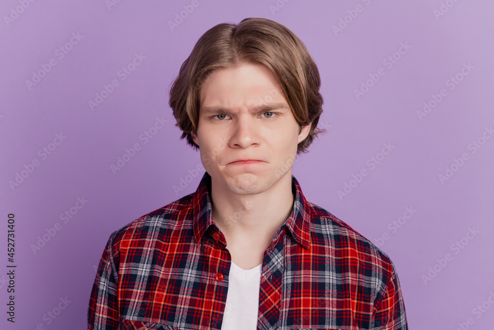 Portrait of grumpy sad dissatisfied guy offended face look camera on purple background