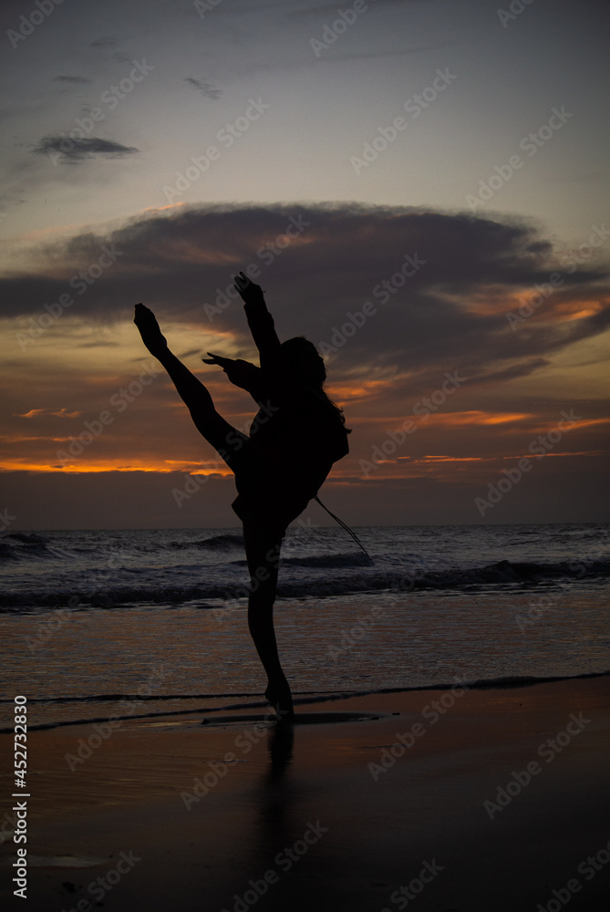 Fototapeta premium silhouette of a person dancing on the beach at sunset