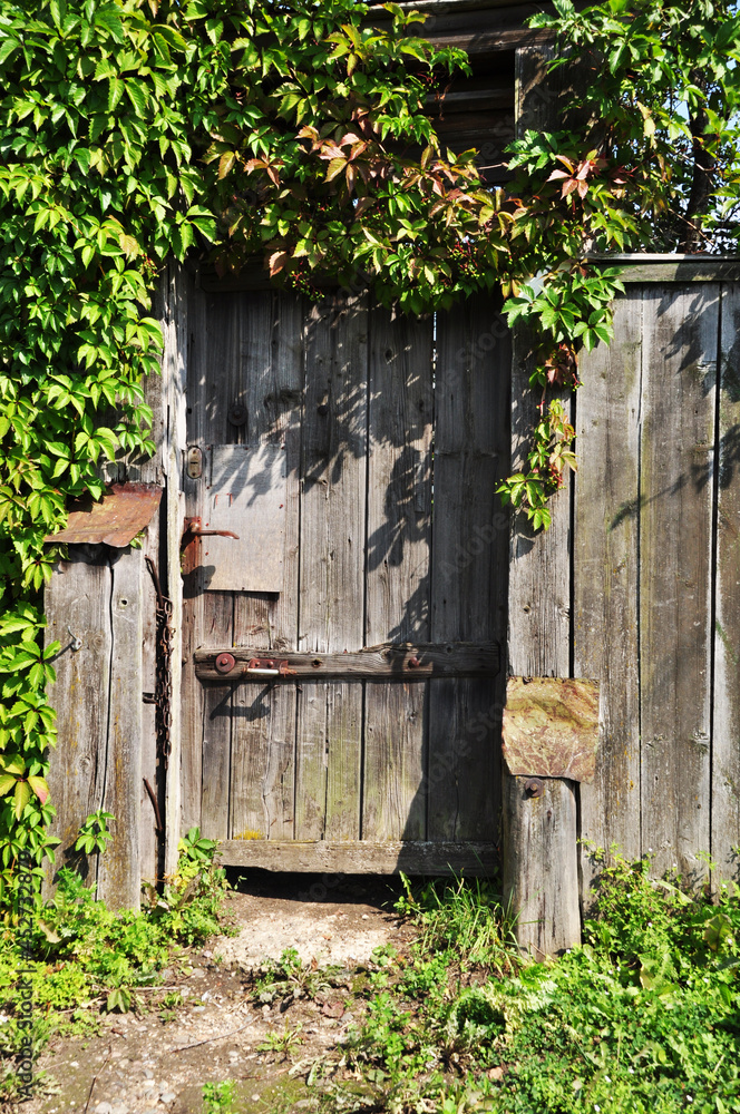 Old wooden door. The front door is made of planks. The boards turned gray. Background, texture. Old wooden door. The front door is made of planks. The boards turned gray. Background, texture.