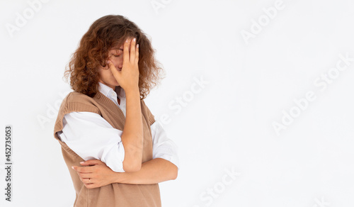 Cute, young beautiful curly hair woman do facepalm. Curly girl headache failed to upset business face palm. Portrait of female doing facepalm posing against studio background. photo