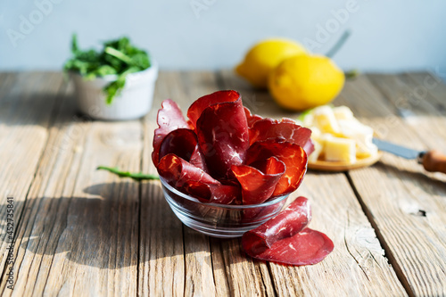 Jerky meat bresaola with lemons, grana and arugula photo