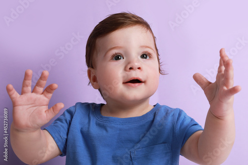 Cute little baby boy on violet background