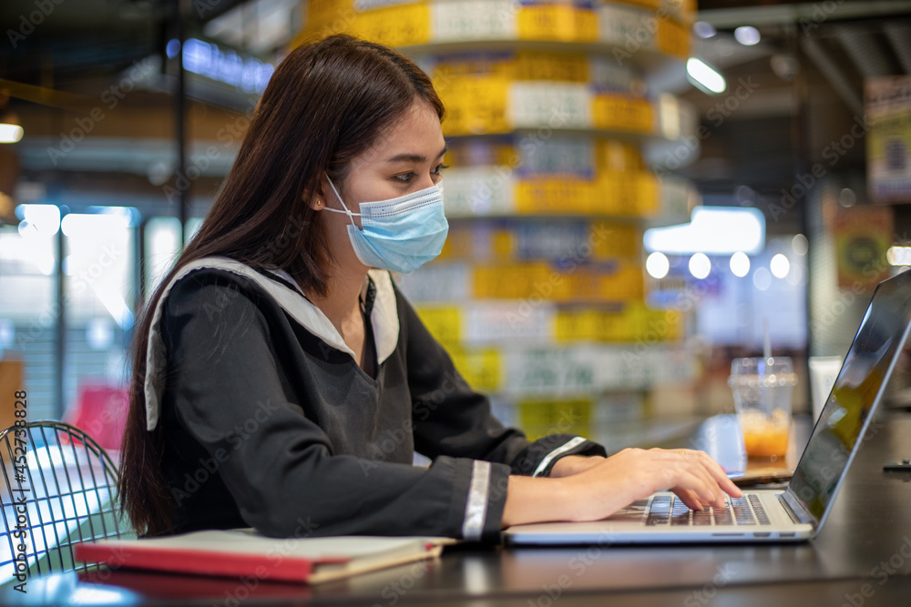 Asian women wearing a mask and she working and studying online with their notebook computers. Asian women wearing a mask and she working and studying online with their notebook computers.