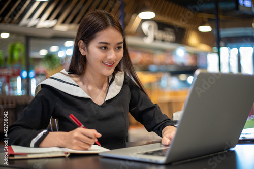 Asian women working and learning online with computer notebook. she smiling and happy