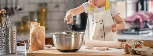 Obraz na plátně Toddler boy playing with the dough in the kitchen dressed as a chef