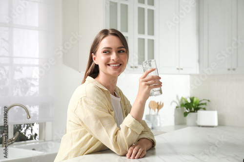 Woman with glass of tap water in kitchen