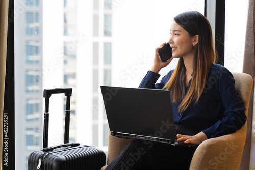 Asian businesswoman using laptop working in hotel room remotely on her business travel