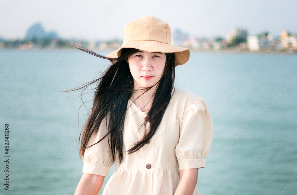 Asian woman wearing a brown hat,A beautiful smiling Asian woman with dark hair shows true positive emotions. Looks happy when wearing fashionable clothes.