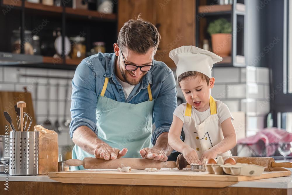 Family together in the kitchen. Father making cake with his toddler son. Family together in the kitchen. Father making cake with his toddler son.