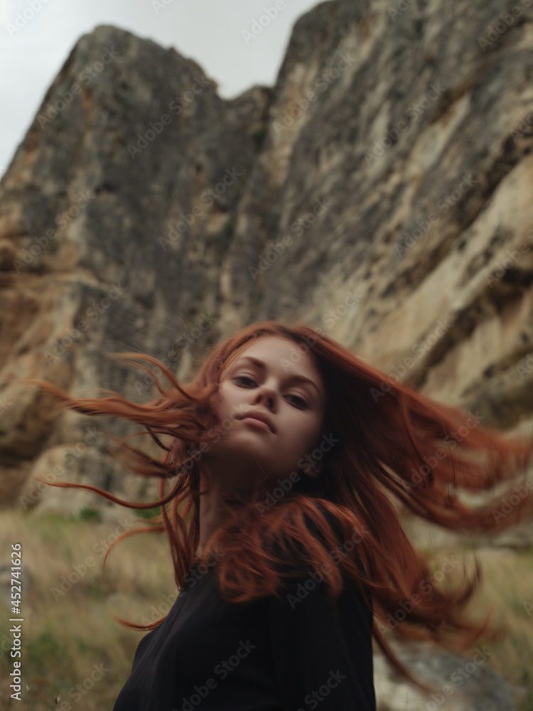Naklejka premium Red-haired woman in the mountains rocks nature romance