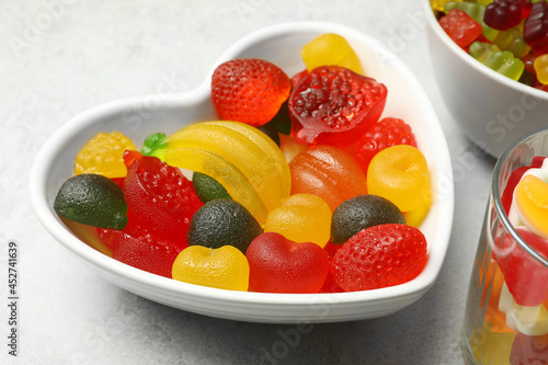 Delicious fruity gummy candies on light grey table  closeup