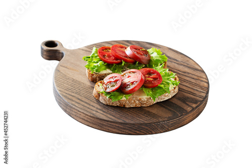 Two sandwiches with soft cottage cheese, tomatoes and salad on a wooden board