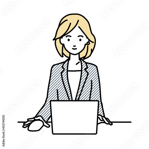 デスクで座ってPCを使っているスーツの女性