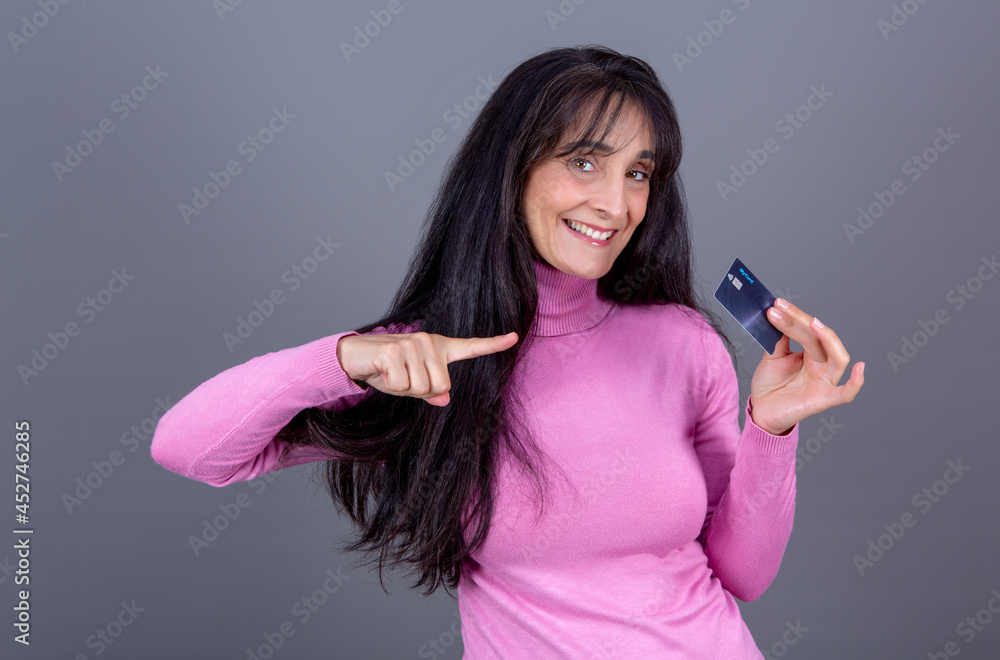 Fototapeta premium Caucasian brunette woman with long hair, smiling, showing credit card