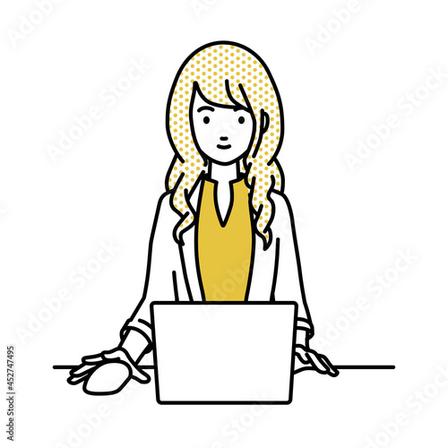 デスクで座ってPCを使っているジャケットの女性