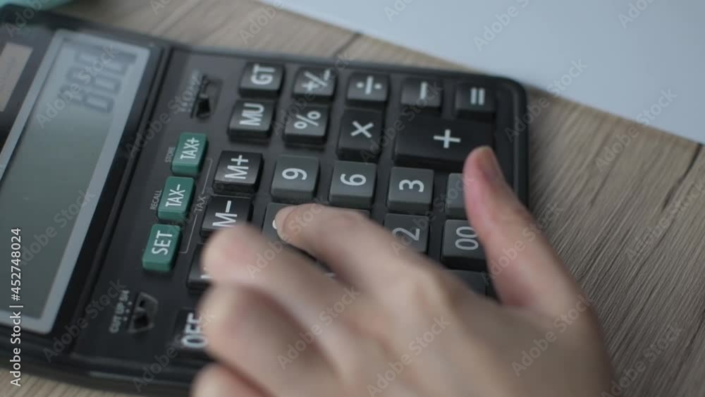 Woman is pressing a calculator to calculate monthly savings to account for monthly income and expenses. Woman is pressing a calculator to calculate monthly savings to account for monthly income and expenses.