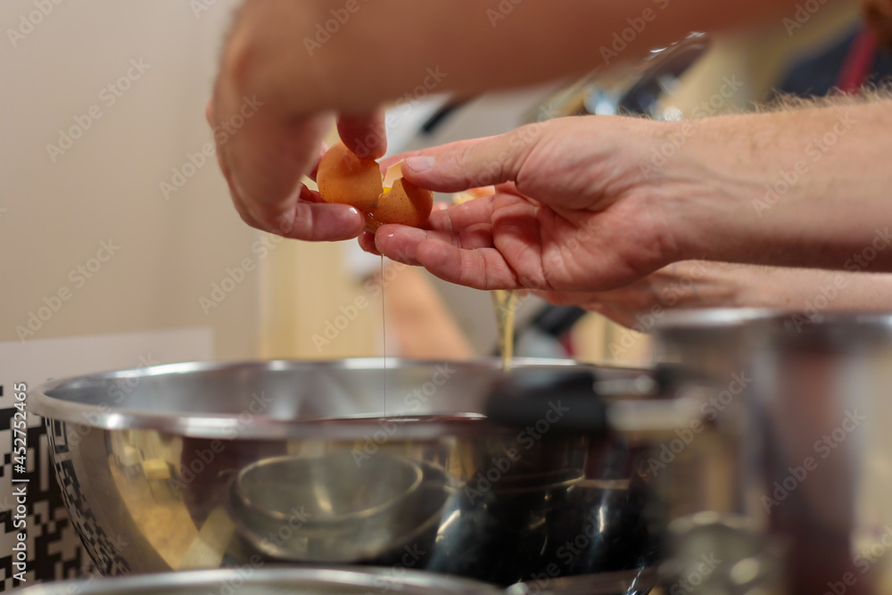 Male hands break a raw egg over a bowl. Cooking a dish of eggs. Close-up.