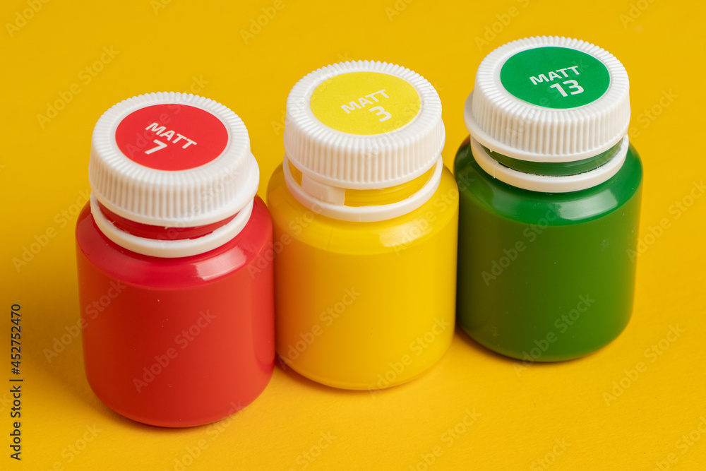 Bottles with multicolored paints on yellow background Bottles with multicolored paints on yellow background