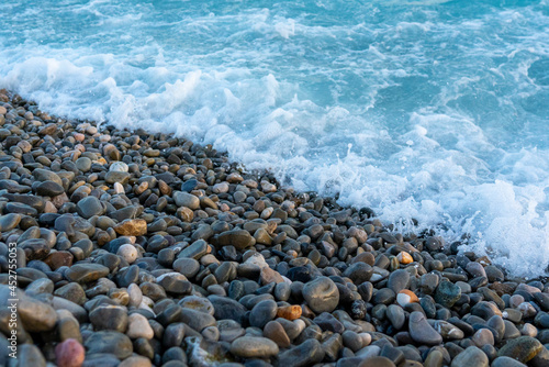 Blue sea water is washed on the stony pebble beach, concept of vacation and freedom 