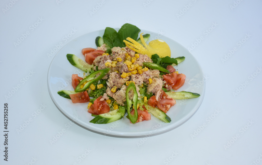  tuna salad fish with tomatoes, arugula, corn served on white plate