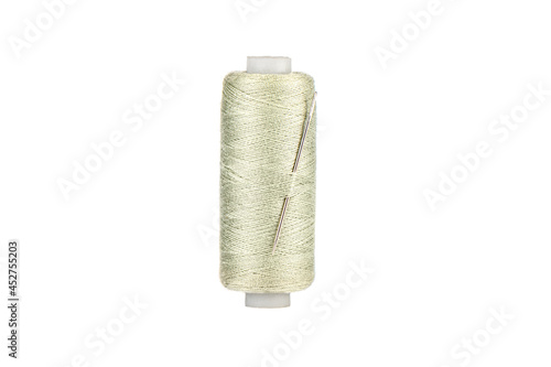 Needle in spool of thread in Tahuna Sands color isolated on white background. Copy space. photo