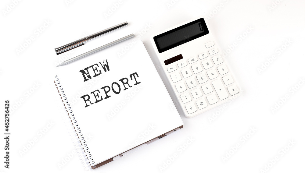 Notepad with text NEW REPORT with calculator and pen. White background. Business concept
