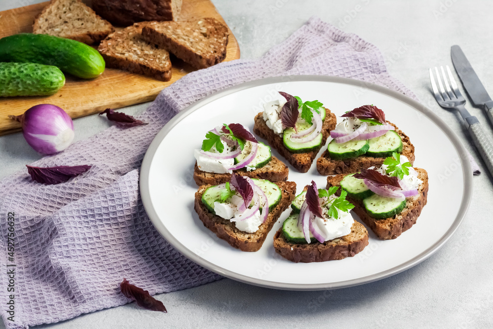 Canapes with toasted bread with sunflower and flax seeds, feta cheese, cucumber and onion