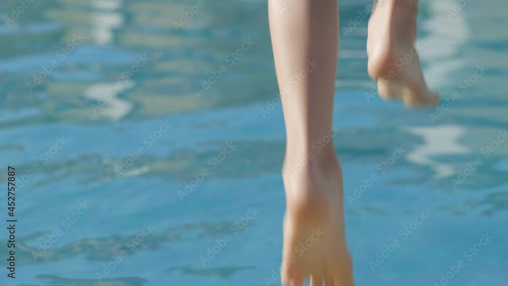 Back view happy girl running and jumping in swimming pool, children having fun, splashing water. Summer travel family hotel vacation tourists Back view happy girl running and jumping in swimming pool, children having fun, splashing water. Summer travel family hotel vacation tourists