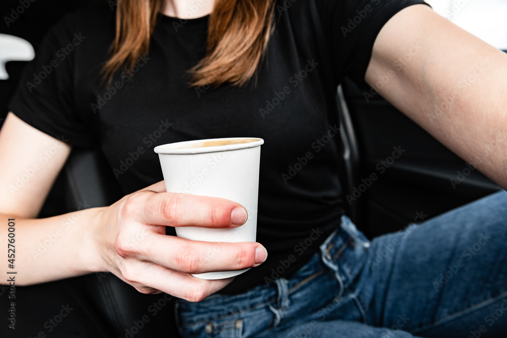 Hand holding paper coffee cup behind the wheel..Takeaway drink. Hand holding paper coffee cup behind the wheel..Takeaway drink.
