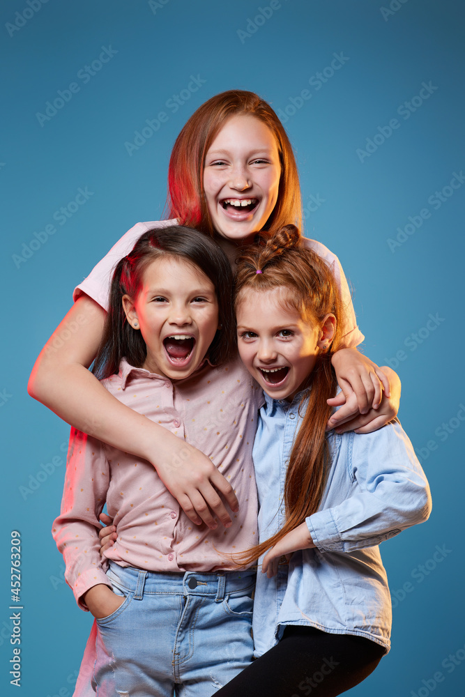 three kids girls standing together on blue background three kids girls standing together on blue background