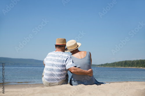 Portrait of senior couple embracing and sitting on the beach sea on a sunny day together