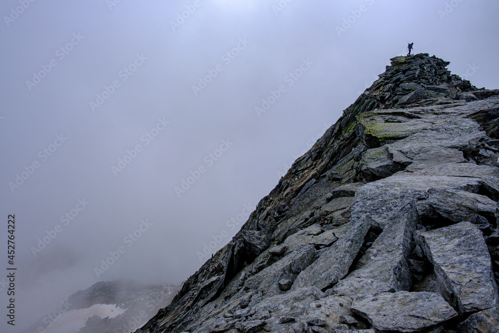 Alpinista sulla vetta di una montagna avvolta nella nebbia