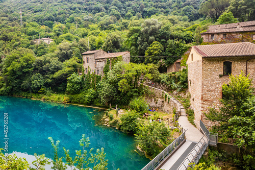 A glimpse of the small village of Stifone, on the Nera river. Umbria, Terni, Italy. The walls of stones and bricks. The bridge over the river with clear blue waters. Tourists stroll through the alleys photo