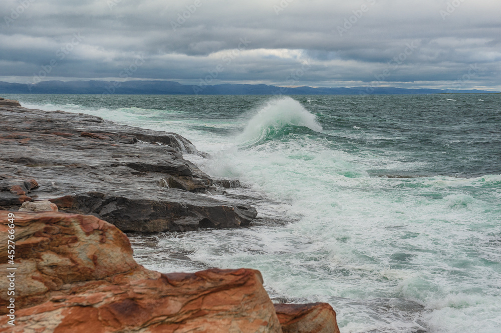 Dramatic scene with Sea waves, rocky seashore and clouds