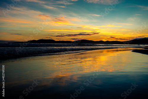 Nascer do sol na praia com nuvens, reflexo e ondas - Paisagem natural © Dales Hoeckesfeld