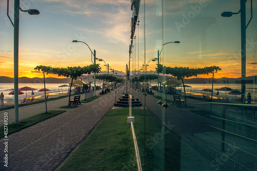 Nascer do sol na praia com nuvens e reflexo em parede de vidro em Itapema - Paisagem natural photo