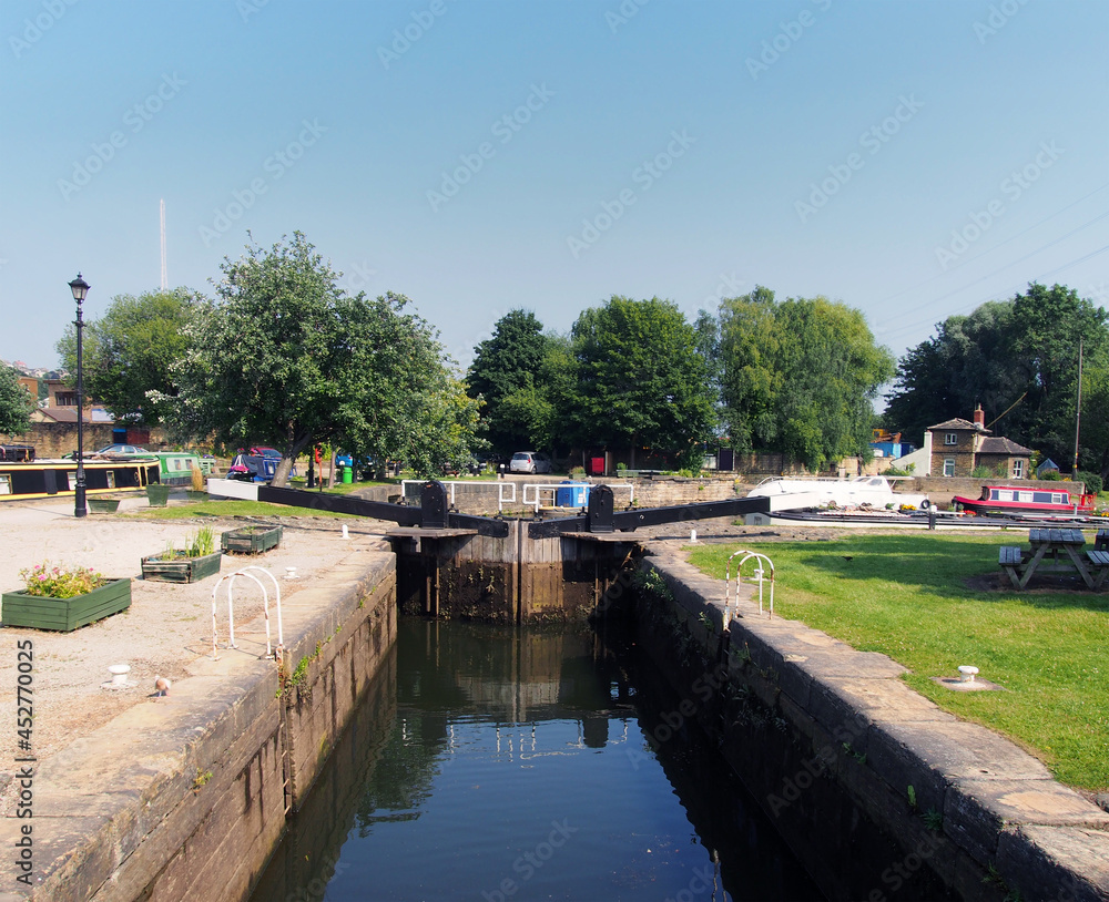 scenic view of lock gate entrance to brighouse basin with boats and moorings on the calder and hebble navigation canal in west yorkshire