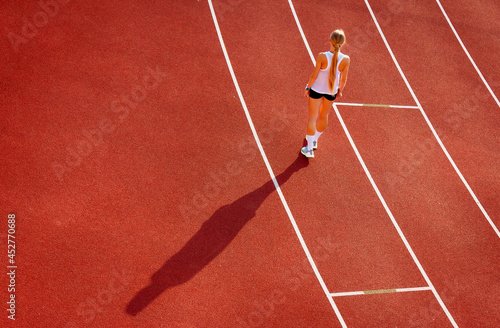 young woman in sports uniform stands on the stadium treadmill, back view. sports training and exercise. healthy lifestyle © x.marynka
