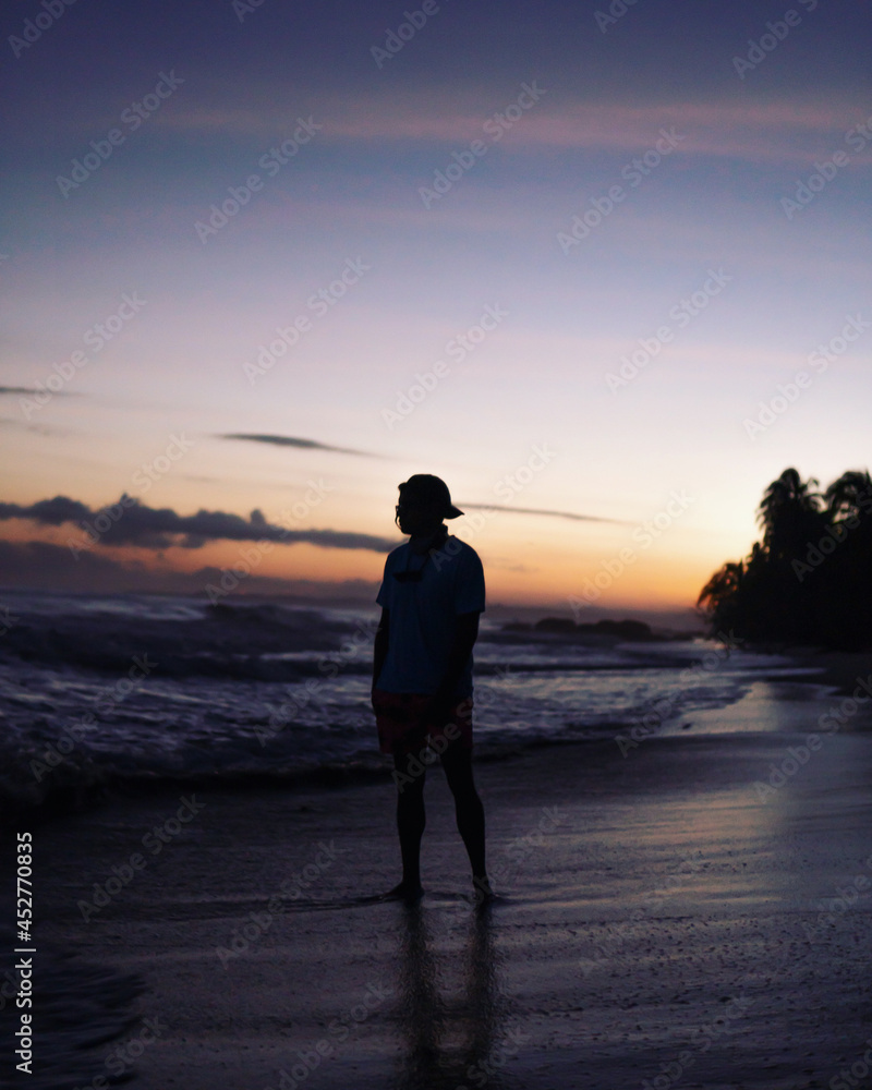 silhouette of a man walking on the beach at sunrise