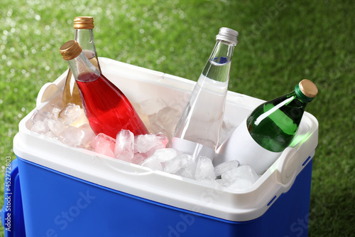 Cuadro en lienzo Blue plastic cool box with drinks and ice cubes on green grass