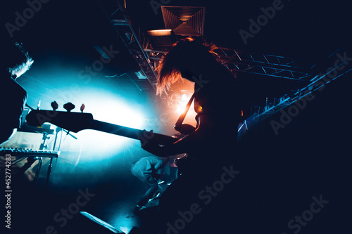 Silhouette Of Guitar Player In Action On Stage. Band Silhouette. View of stage during rock concert with musical instruments and scene stage lights, rock show performance. Guitarist plays solo on stage