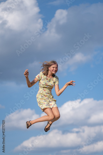 Young beautiful girl photographed in a jump against the background of the sky.