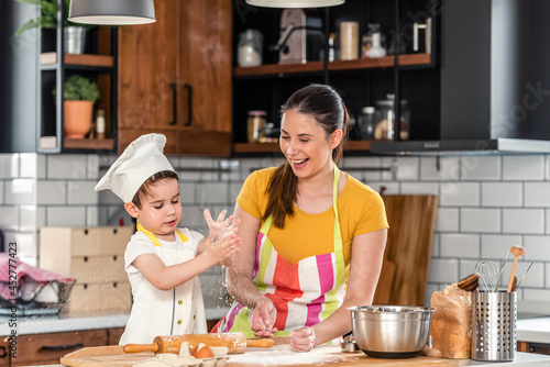 Mother baking cake in the kitchen with her cute toddler son. Mother and child having quality time together.