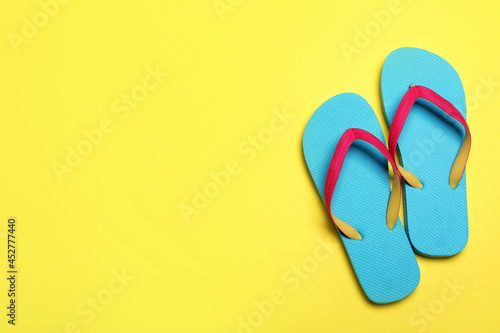 Stylish flip flops on yellow background, flat lay. Space for text