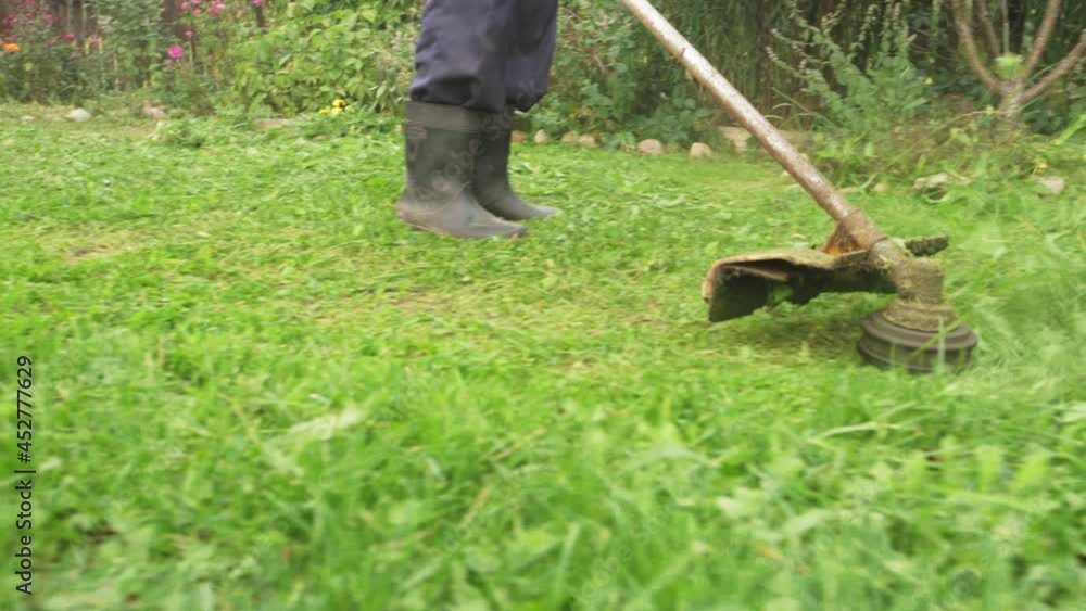 work to mow the grass trimmer. process of mowing tall grass with a trimmer Stock Video Adobe Stock