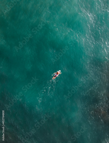 girl surfer from aerial view in the middle of the sea