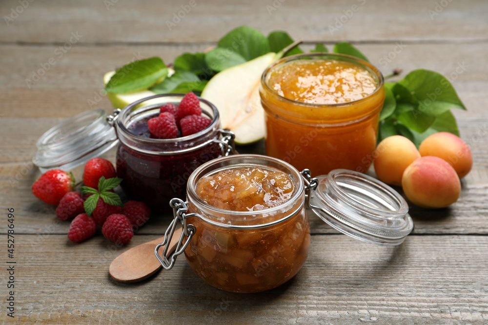 Jars with different jams and fresh fruits on wooden table Jars with different jams and fresh fruits on wooden table