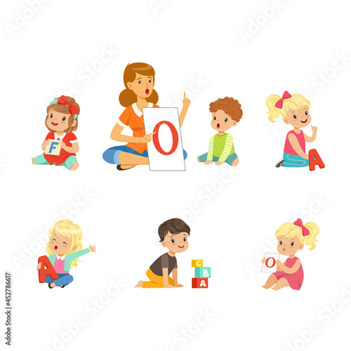 Cute Children Learning Alphabet and Playing in Nursery School with Teacher Sitting on the Floor with Card and Cube Vector Set