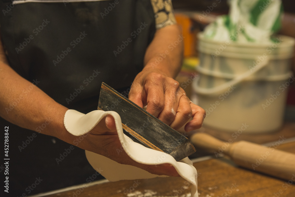 Obraz premium Worker preparing typical Mexican sweets made from Alfeñique, used during the Dia de Muertos festival to put on altars. The person's hands and the molds and the dough are distinguished.